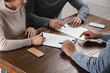 © New Africa - Notary helping couple with paperwork at wooden table, closeup