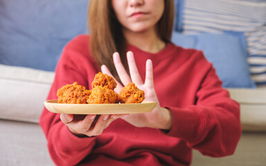 Wall Mural - Closeup of a woman making hand sign to refuse fried chicken for dieting and healthy eating concept