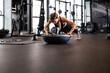 © ty - Portrait of a muscular woman on a plank position with bosu at gym.