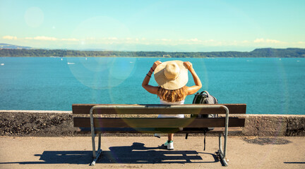 Wall Mural - Woman sitting on bench looking at lake ( Switzerland )