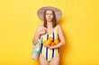 © sementsova321 - Disappointed woman wearing swimsuit isolated on yellow background holding fruit looking at camera with offended facial expression being sad.