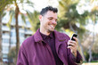 © luismolinero - Young caucasian man at outdoors sending a message or email with the mobile