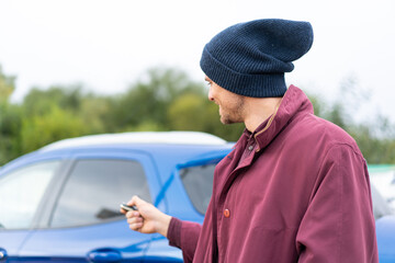 Wall Mural - Young caucasian man holding car keys at outdoors