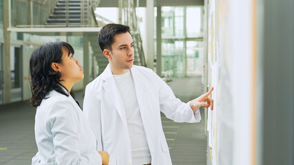 Poster - Multinational group in white coats having a conversation in a research facility.