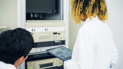 Poster - Multinational group operating electronic devices while looking at tablet.