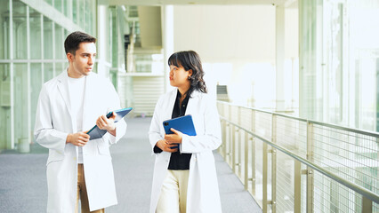 Poster - Multinational group walking in the lobby wearing white coats.