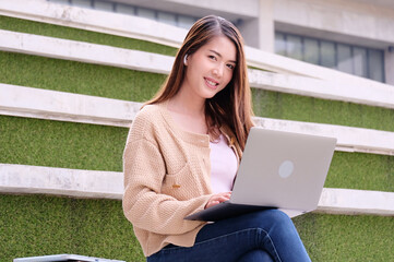 Happy smiling young woman sitting and studying data on laptop.