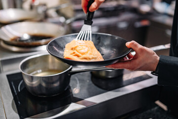 Poster - man chef hand cooking one big Ravioli on restaurant kitchen