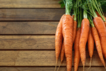 Wall Mural - Bunch of fresh young carrots with haulm on a wooden table with copy space