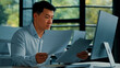 © Yuliia - Tired unhappy Asian man worker manager sit at office doing routine paperwork read contract documents budget invoice pay bills online analyze business plan check documentation professional paper audit