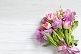 Fototapeta Tulipany - Beautiful bouquet of colorful tulip flowers on white wooden table, top view. Space for text