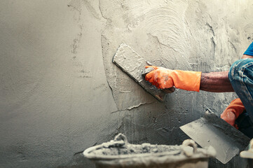 hand of worker plastering cement at wall for building house