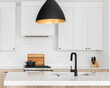 A kitchen detail with white and white oak cabinets, a subway tile backsplash, and a black and gold light hanging above. No names or brands.
