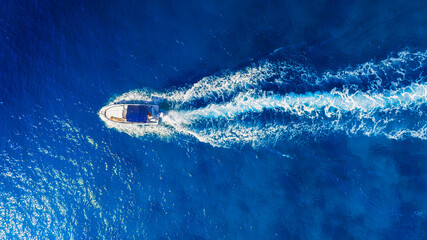 Wall Mural - A fast boat on an azure sea. Clear turquoise water and a boat. View from the air. Summer landscape from a drone. Rest and travel in the summer time. The season for vacation. Photography for design.