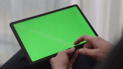 Sticker - Man sitting indoors on a chair with tablet pc with green screen