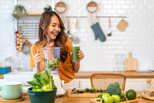 Portrait Of Beauty Healthy Asian Woman Making Green Vegetables Detox Cleanse And Green Fruit Smoothie With Blender.young Girl Drinking Glass Of Green Fruit Smoothie In Kitchen.Diet Concept.healthy 