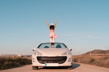 Vertical Shot European Girl Dressed In Pink Outdoors In Her Convertible Car On A Highway During The Summer Vacation -