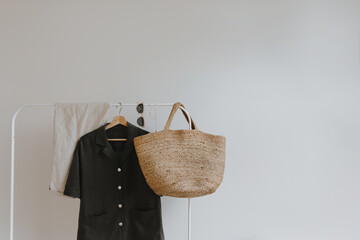 Wall Mural - Trendy female wardrobe. Stylish women's summer clothes on hanger. Trousers, rattan bag, shirt, sunglasses