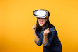 © Jirawatfoto - Young asian woman get experienced wearing virtual reality headset game entertainment isolated on yellow background. Winner of cyber future video game concept.