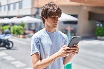 Sticker - Young blond man using touchpad with serious expression at street