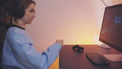 Wall Mural - Teenager girl playing video game at home. Gamer holding gamepads sitting at front of screen. Streamer playing online in dark room lit by neon lights. Competition and having fun