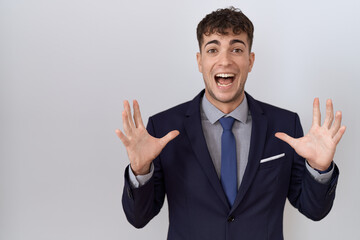 Poster - Young hispanic business man wearing suit and tie celebrating crazy and amazed for success with arms raised and open eyes screaming excited. winner concept