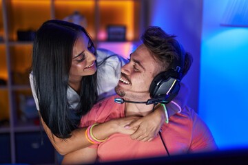 Wall Mural - Man and woman streamers playing video game hugging at gaming room