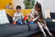 © Krakenimages.com - Adorable boy and girl playing with hoops game sitting on sofa at home