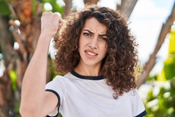 Sticker - Hispanic woman with curly hair standing outdoors annoyed and frustrated shouting with anger, yelling crazy with anger and hand raised