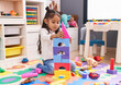 © Krakenimages.com - Adorable hispanic girl playing with construction blocks sitting on floor at kindergarten