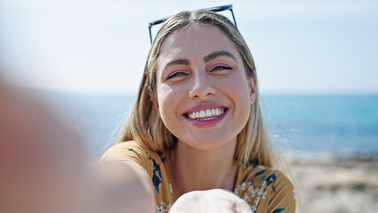 Wall Mural - Young blonde woman smiling confident make selfie by camera at seaside