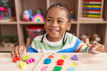 African American Boy Playing With Maths Puzzle Game Sitting On Table At Kindergarten