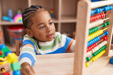 African American Boy Playing With Abacus Sitting On Table At Kindergarten