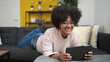 © Krakenimages.com - Young african american woman using touchpad lying on sofa at home