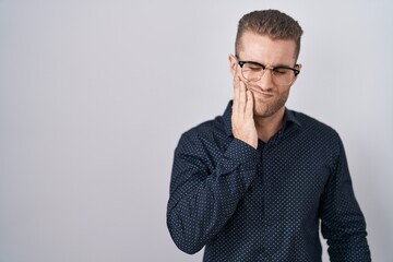 Wall Mural - Young caucasian man standing over isolated background touching mouth with hand with painful expression because of toothache or dental illness on teeth. dentist