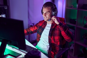 Poster - Young caucasian man streamer playing video game using computer at gaming room