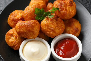 Battered chicken balls with tomato ketchup, mayonnaise on black plate. Party food