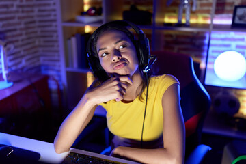 Wall Mural - Young african american woman streamer sitting on table with doubt expression at gaming room