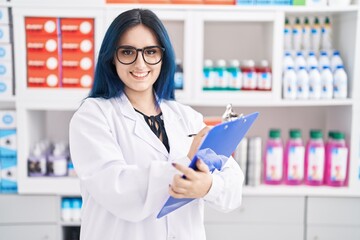 Wall Mural - Young caucasian woman pharmacist smiling confident writing on document at pharmacy