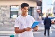 © Krakenimages.com - Young hispanic man smiling confident using touchpad at street