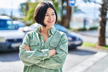 Canvas Print - Young chinese woman smiling confident standing with arms crossed gesture at street