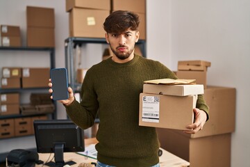 Sticker - Arab man with beard working at small business ecommerce holding delivery packages skeptic and nervous, frowning upset because of problem. negative person.