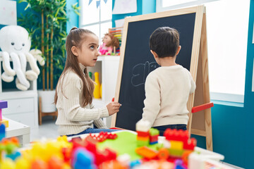 Wall Mural - Adorable boy and girl preschool students drawing on blackboard at kindergarten