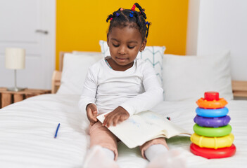 Wall Mural - African american girl sitting on bed reading book at bedroom