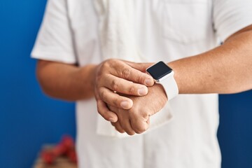 Poster - Young latin man touching stopwatch at sport center