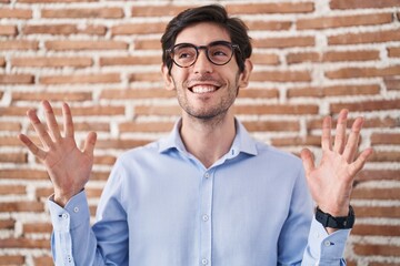 Poster - Young hispanic man standing over brick wall background celebrating mad and crazy for success with arms raised and closed eyes screaming excited. winner concept