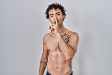 Poster - Hispanic man standing shirtless asking to be quiet with finger on lips. silence and secret concept.