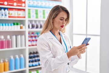 Wall Mural - Young beautiful hispanic woman pharmacist using smartphone working at pharmacy