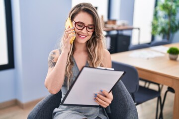 Wall Mural - Young woman business worker talking on smartphone reading document at office