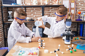 Wall Mural - Adorable boys student pouring liquid on test tube at laboratory classroom